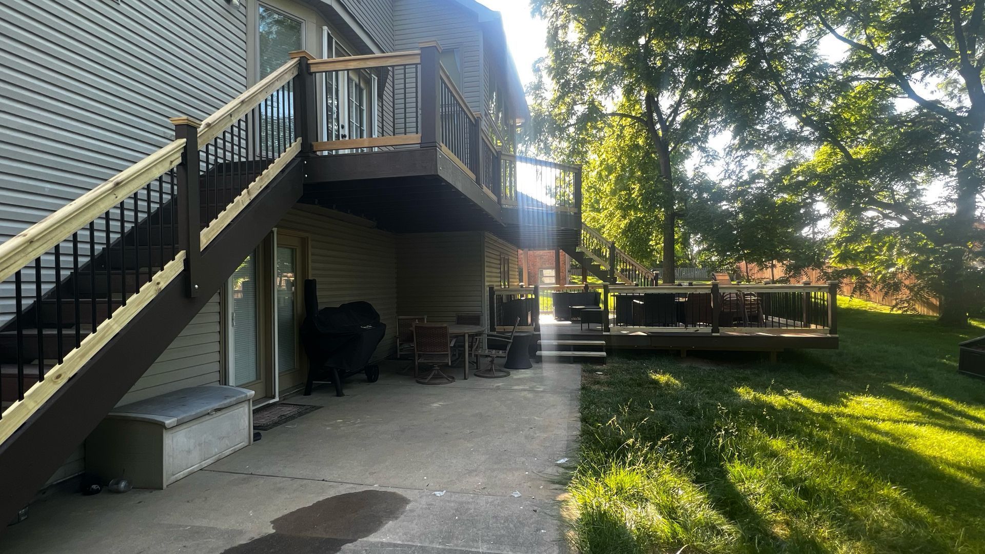 Backyard deck with stairs, shaded patio, and grassy yard beside a house