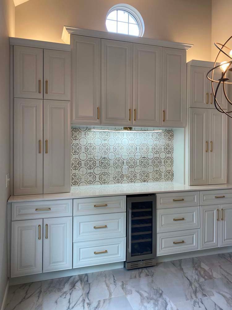 Built-in white cabinets and drawers with a decorative tile backsplash and marble floor in a kitchen nook