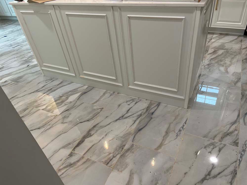 White paneled kitchen island on glossy gray marble floor tiles.