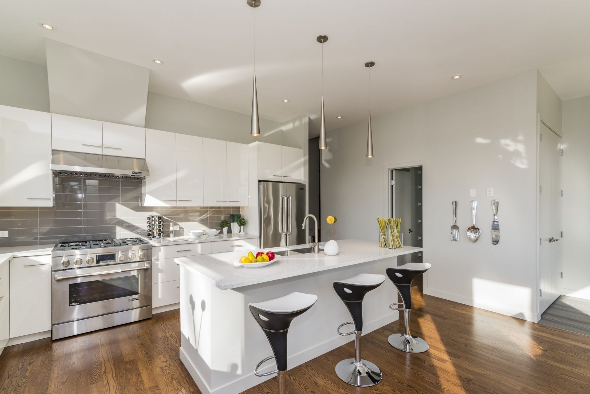 Bright modern kitchen with white cabinets, island, bar stools, and stainless steel appliances