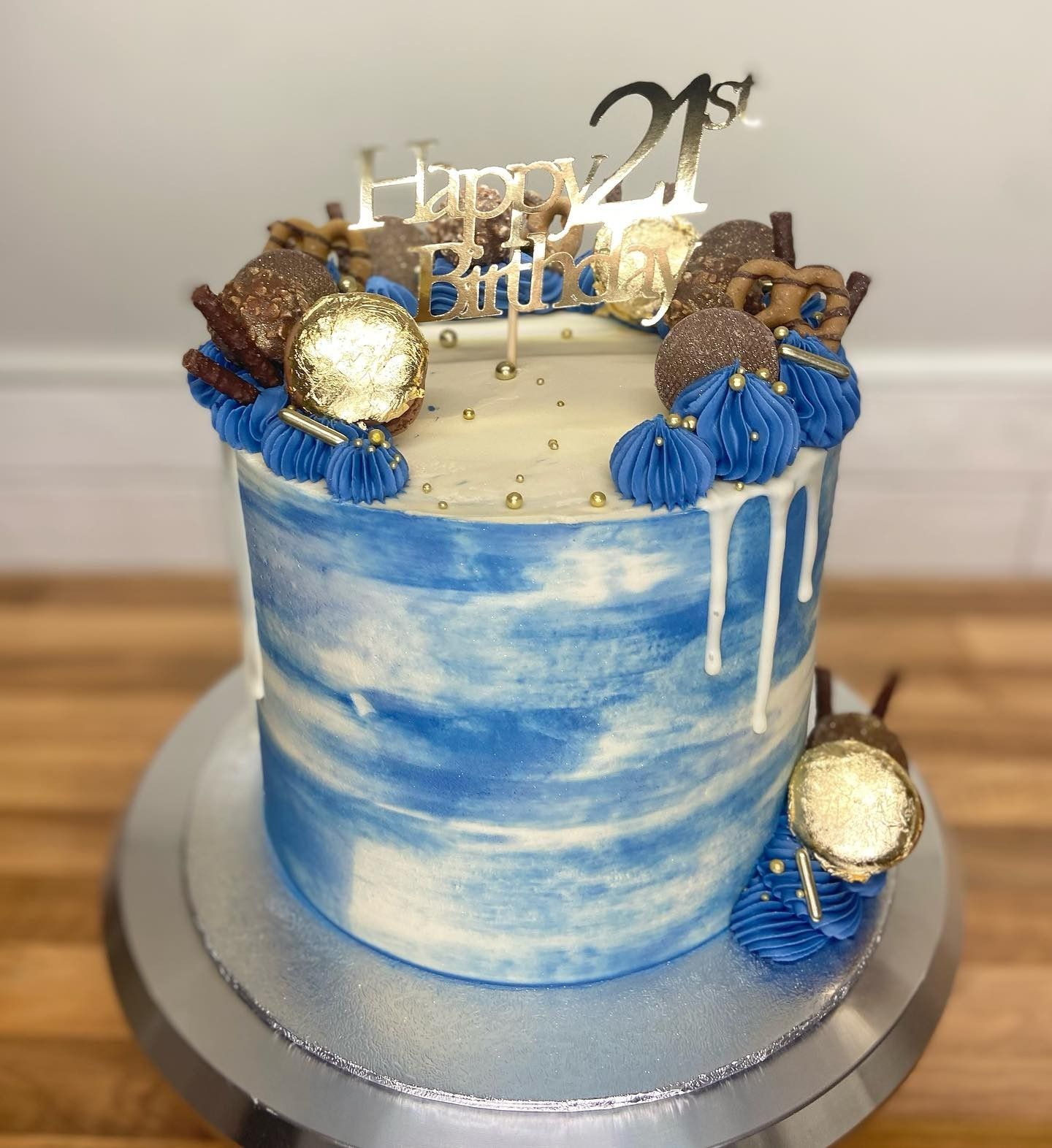 A blue and white birthday cake with a happy birthday topper