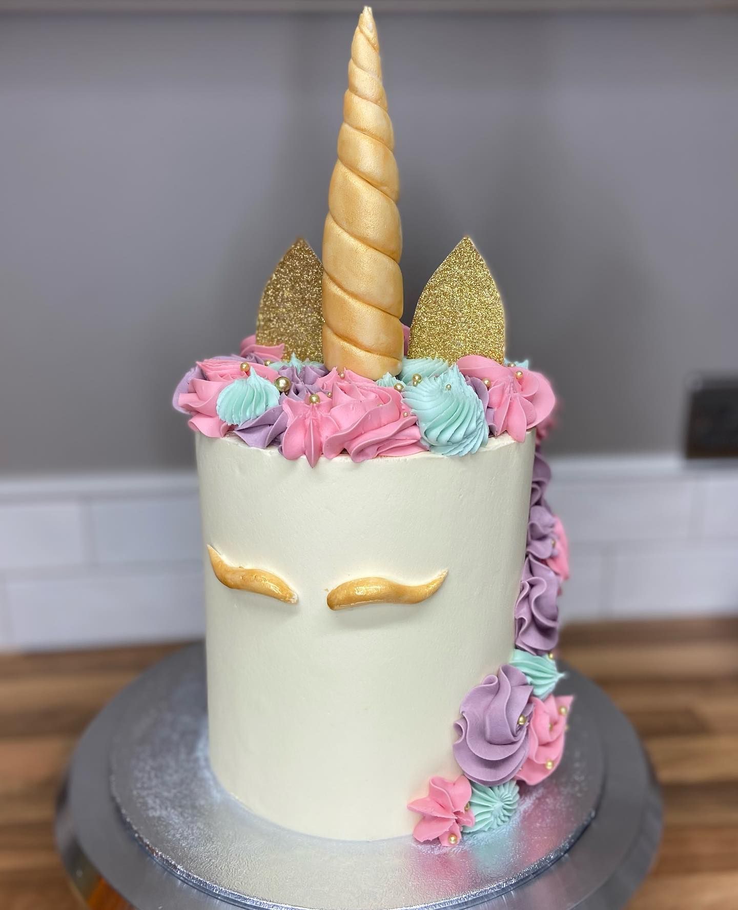 A unicorn cake with flowers and a horn on top of it.