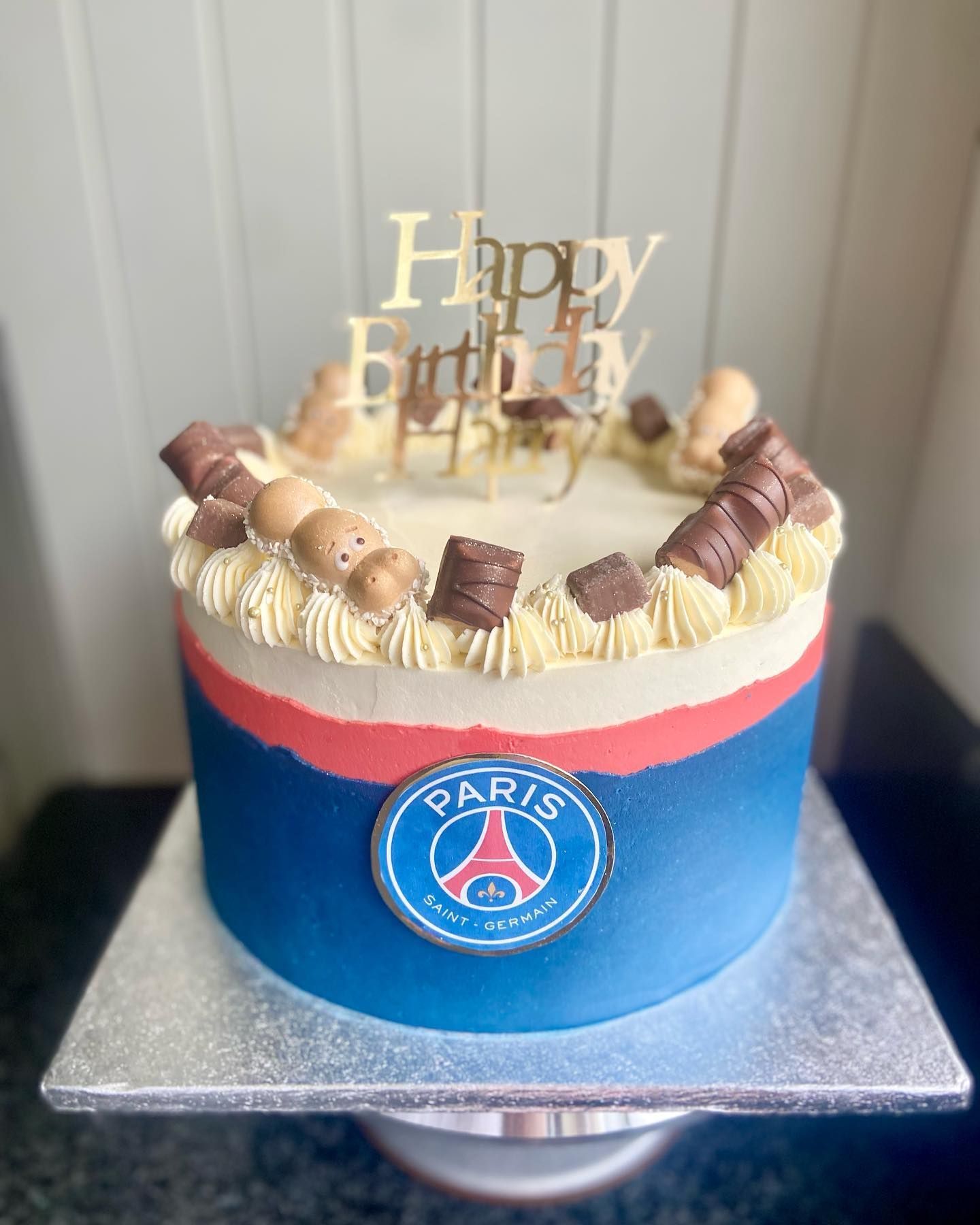 A birthday cake with a paris logo on it is sitting on a table.