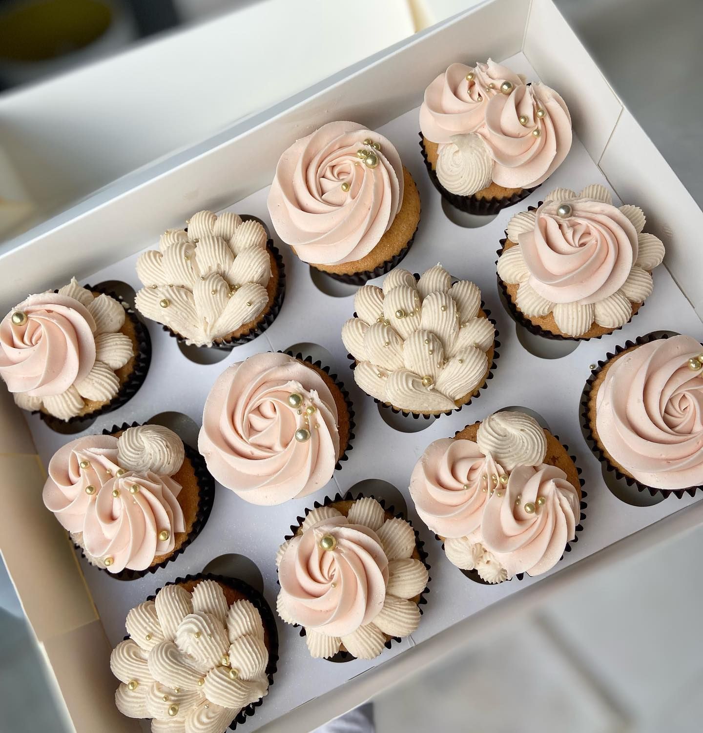 A box of cupcakes with pink frosting on them