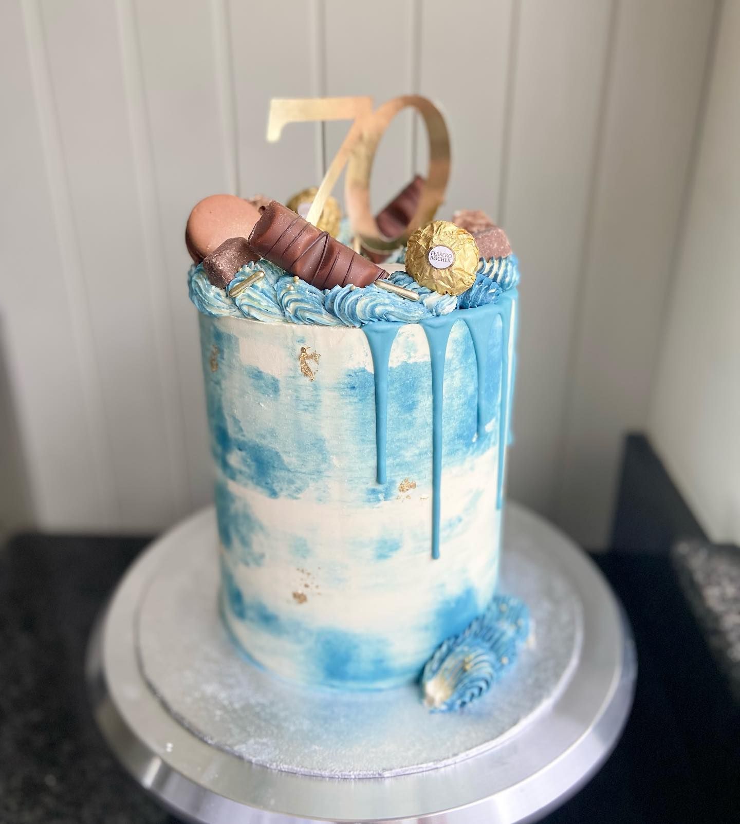 A blue and white cake is sitting on top of a cake stand.