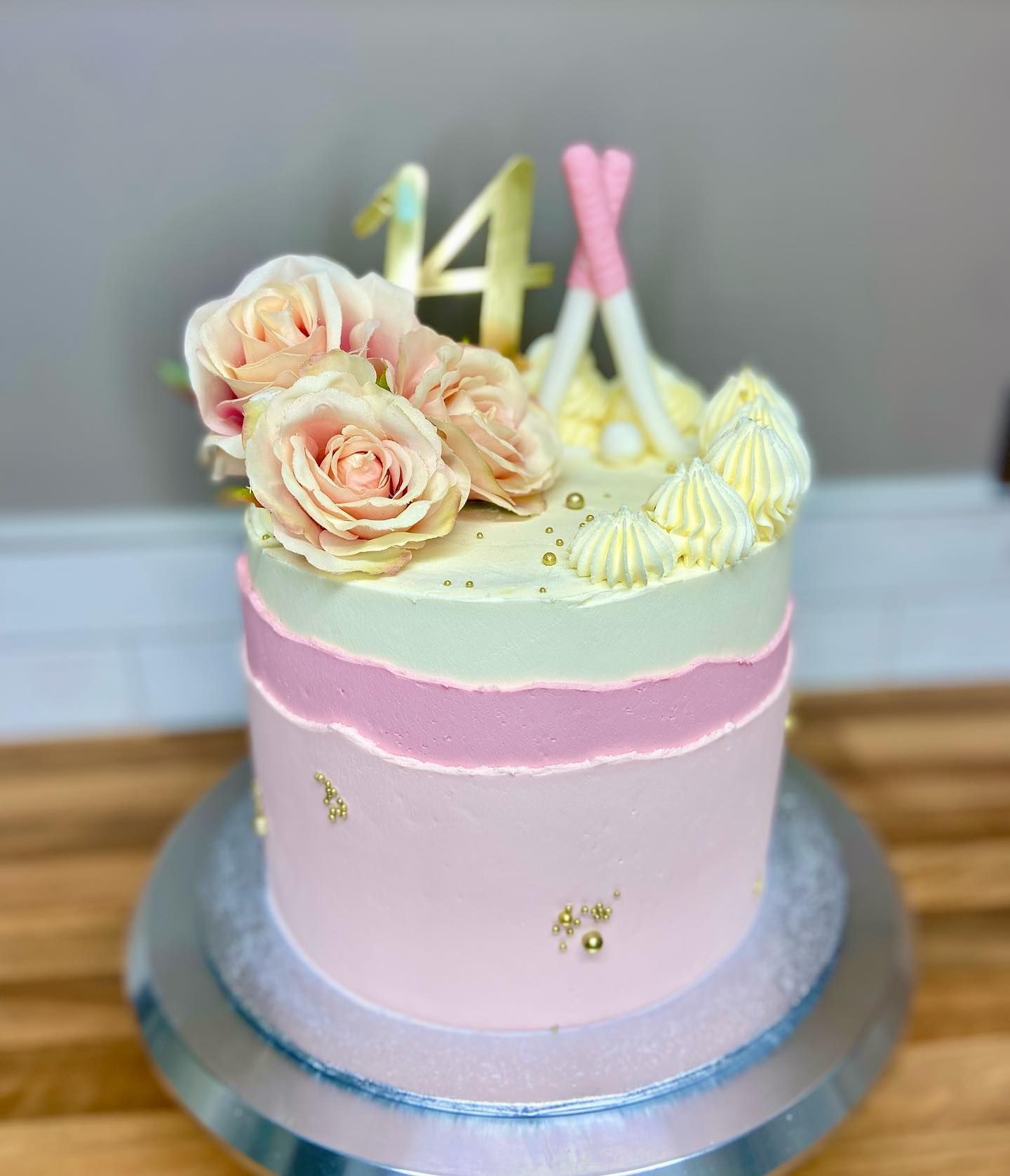A pink and white cake with flowers and the number 14 on top.