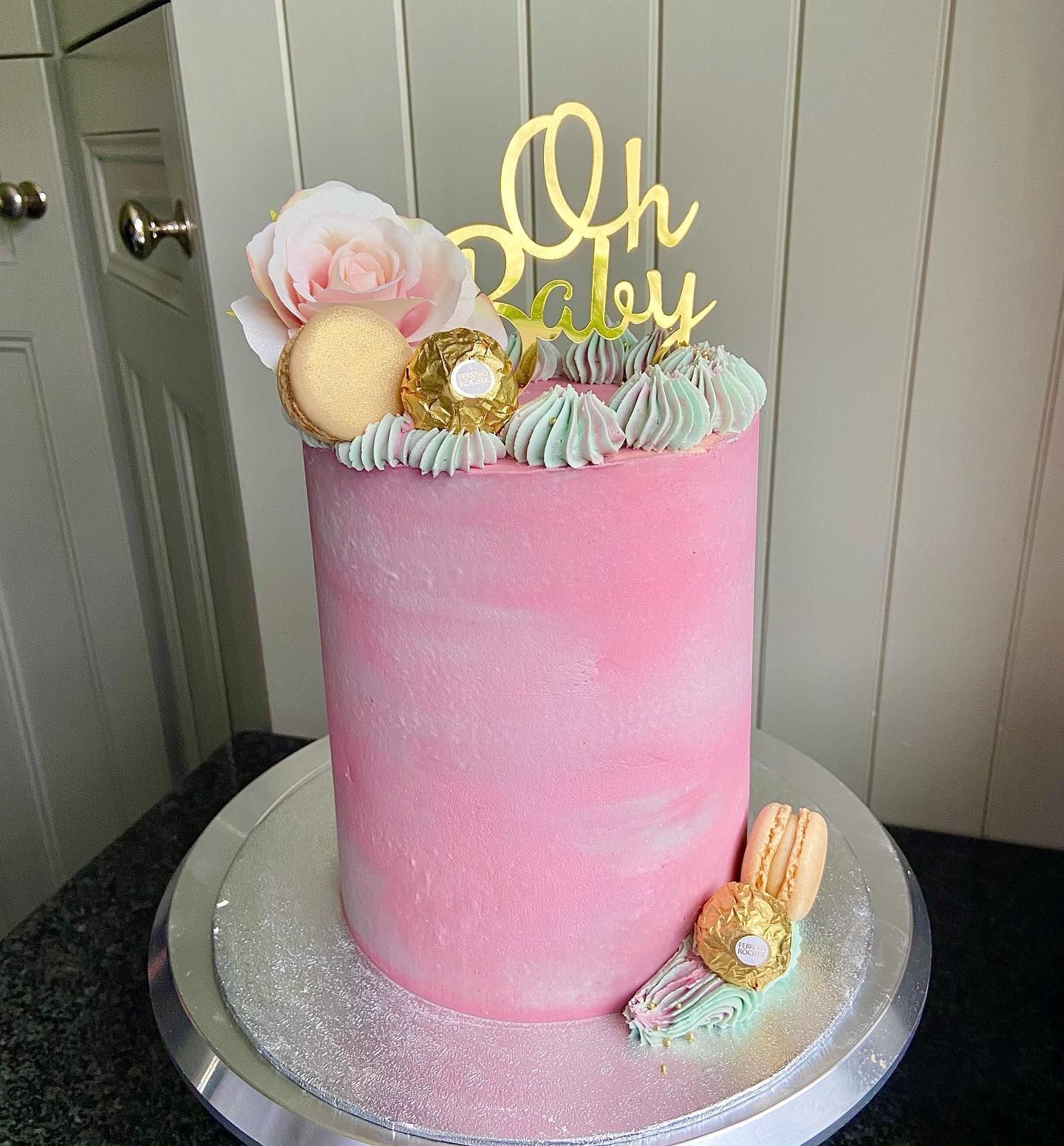 A pink cake with a topper that says `` oh baby ''