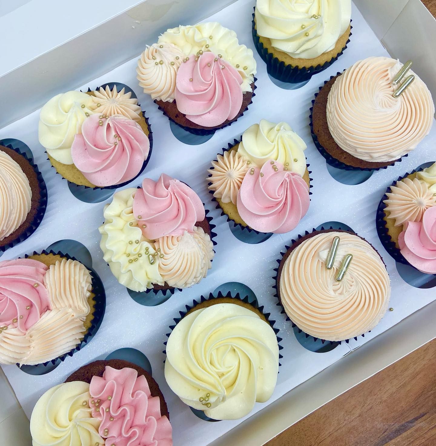 A box of cupcakes with pink and white frosting