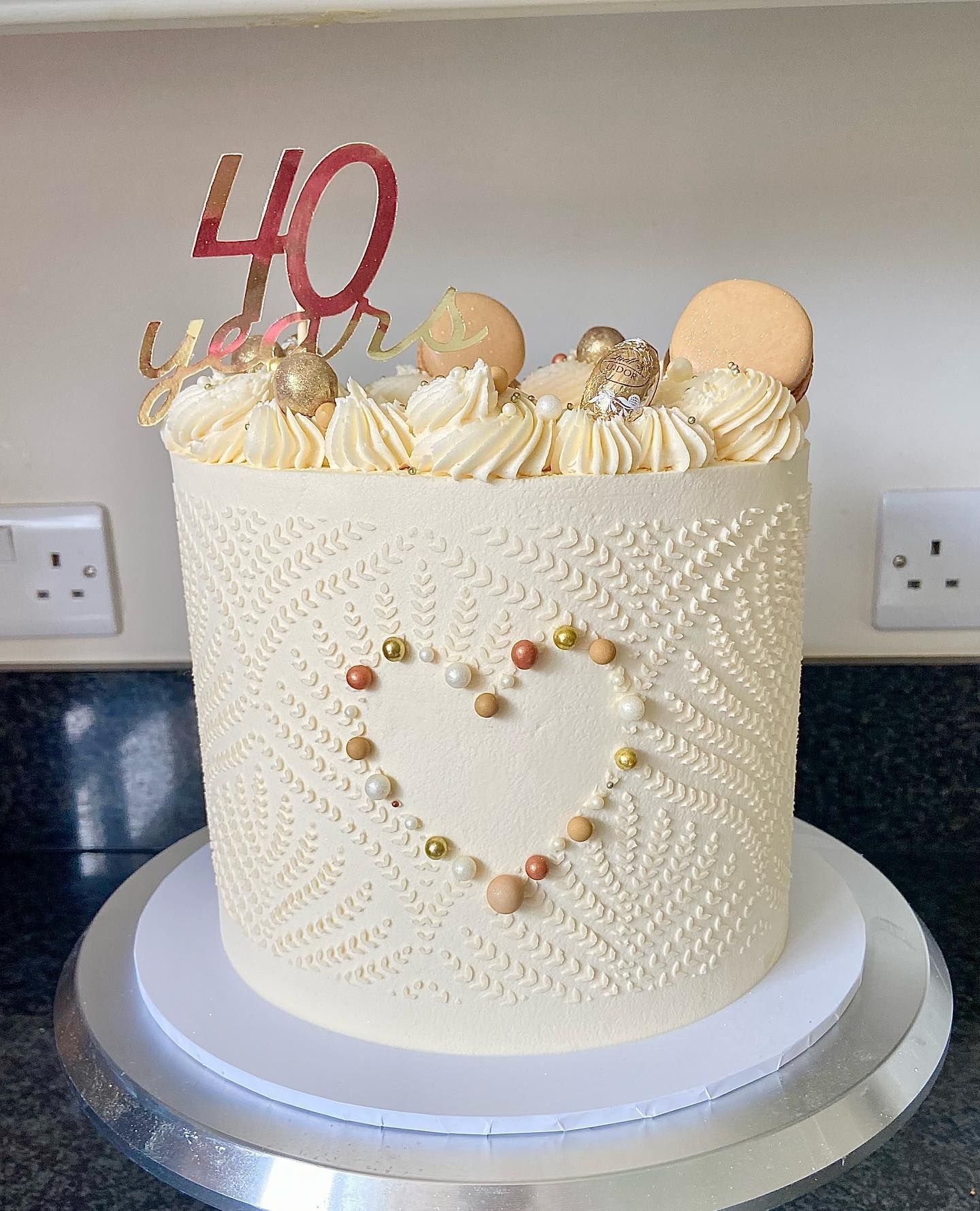 A white cake with a heart and the number 40 on top of it.