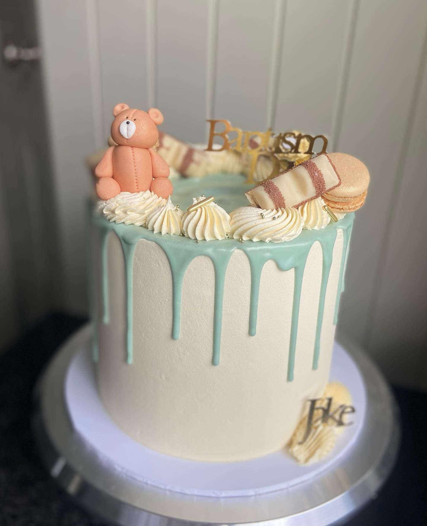 A cake with a teddy bear on top of it is on a cake stand.
