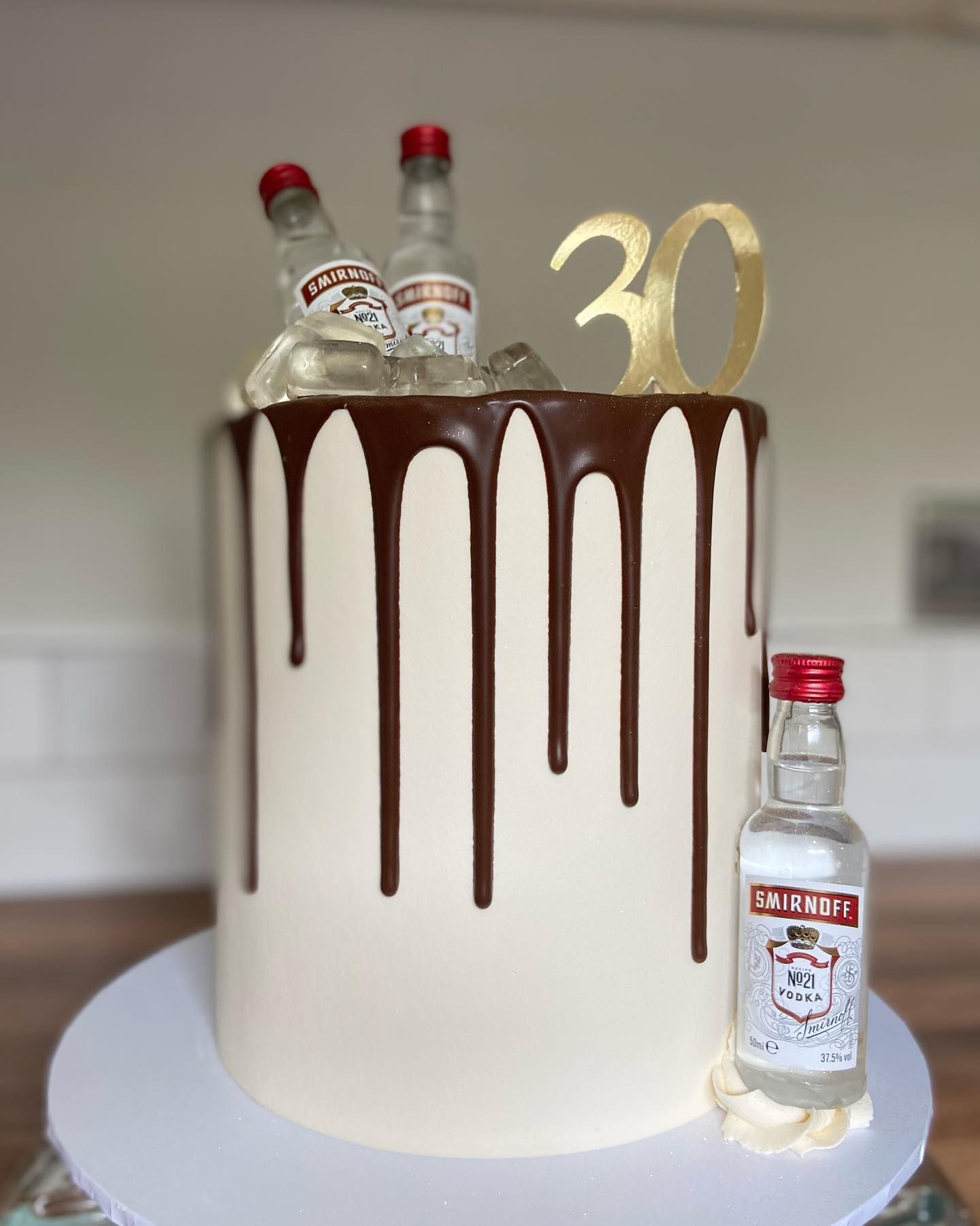 A cake with a bottle of smirnoff on top of it.
