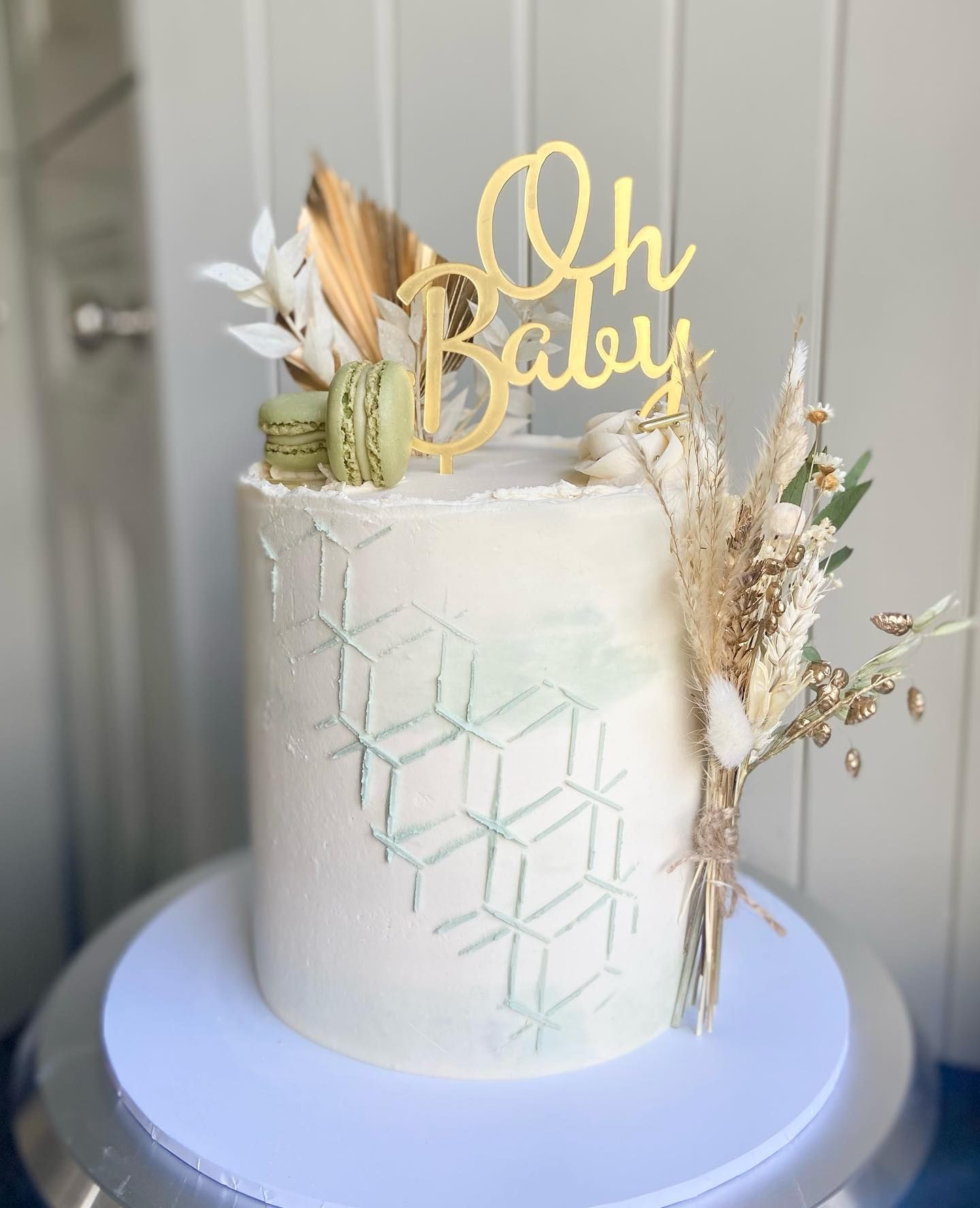 A white cake with a gold oh baby cake topper on top of it.