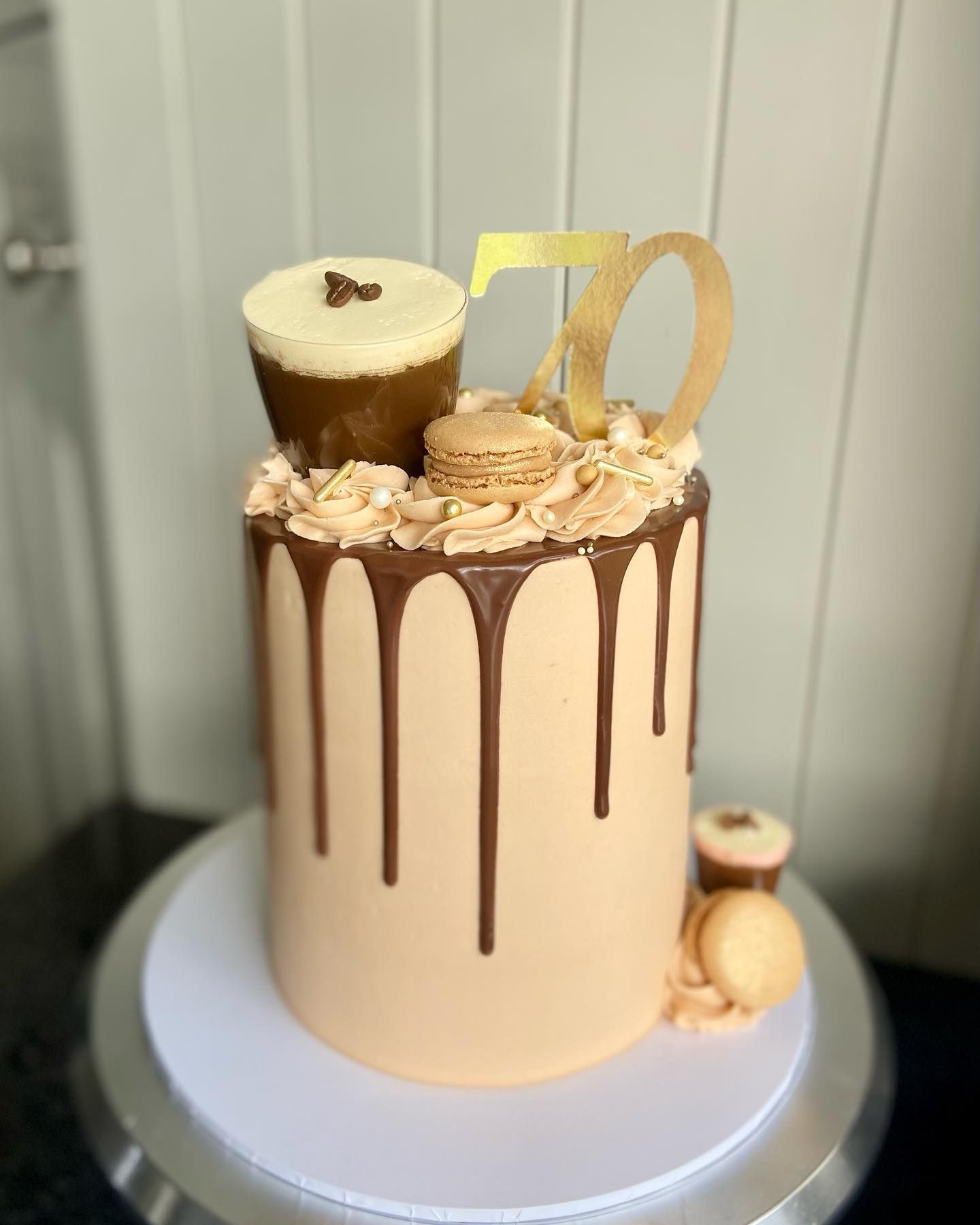 A cake with a number 70 on top of it is sitting on top of a cake stand.