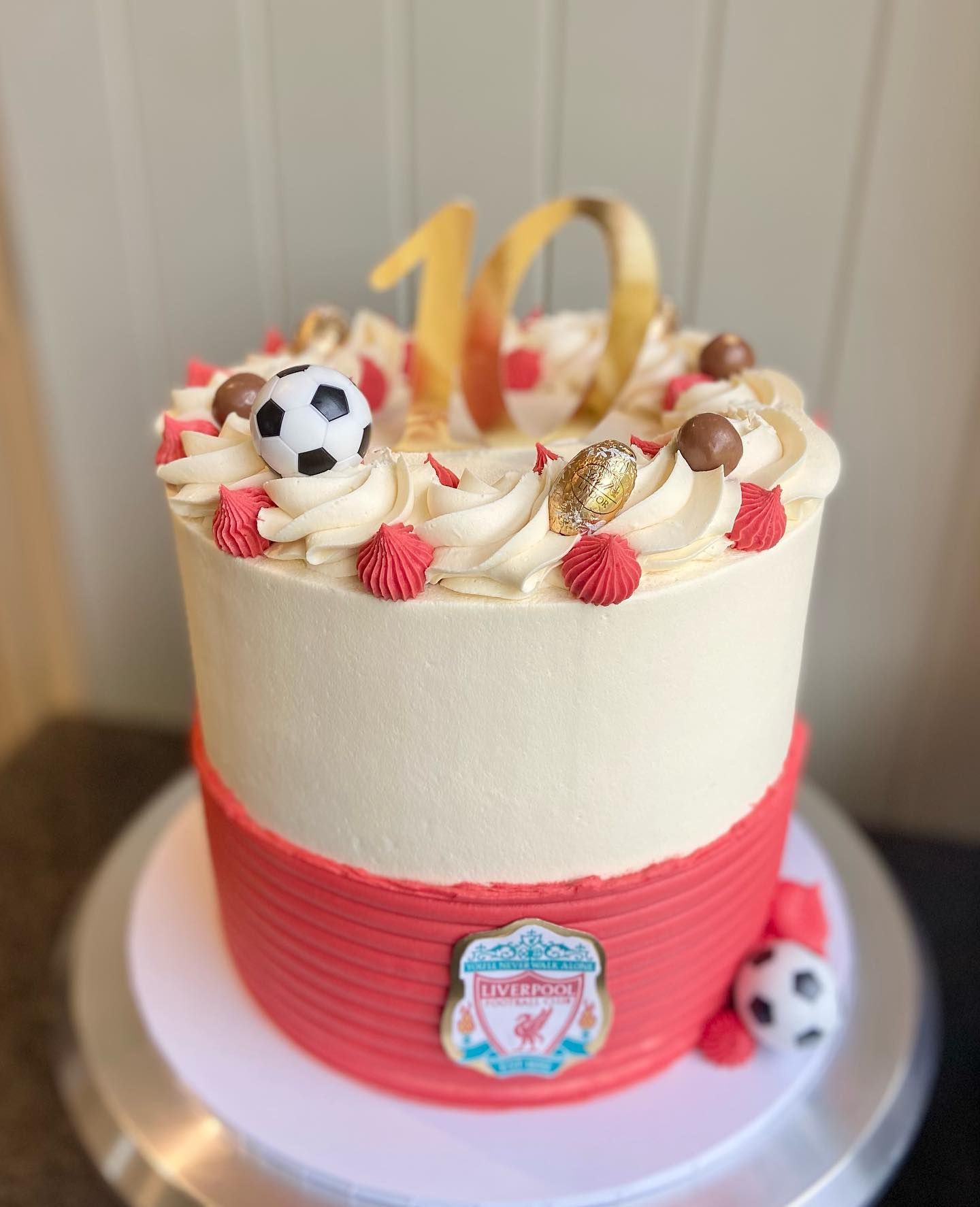 A red and white cake with a soccer ball on top of it.
