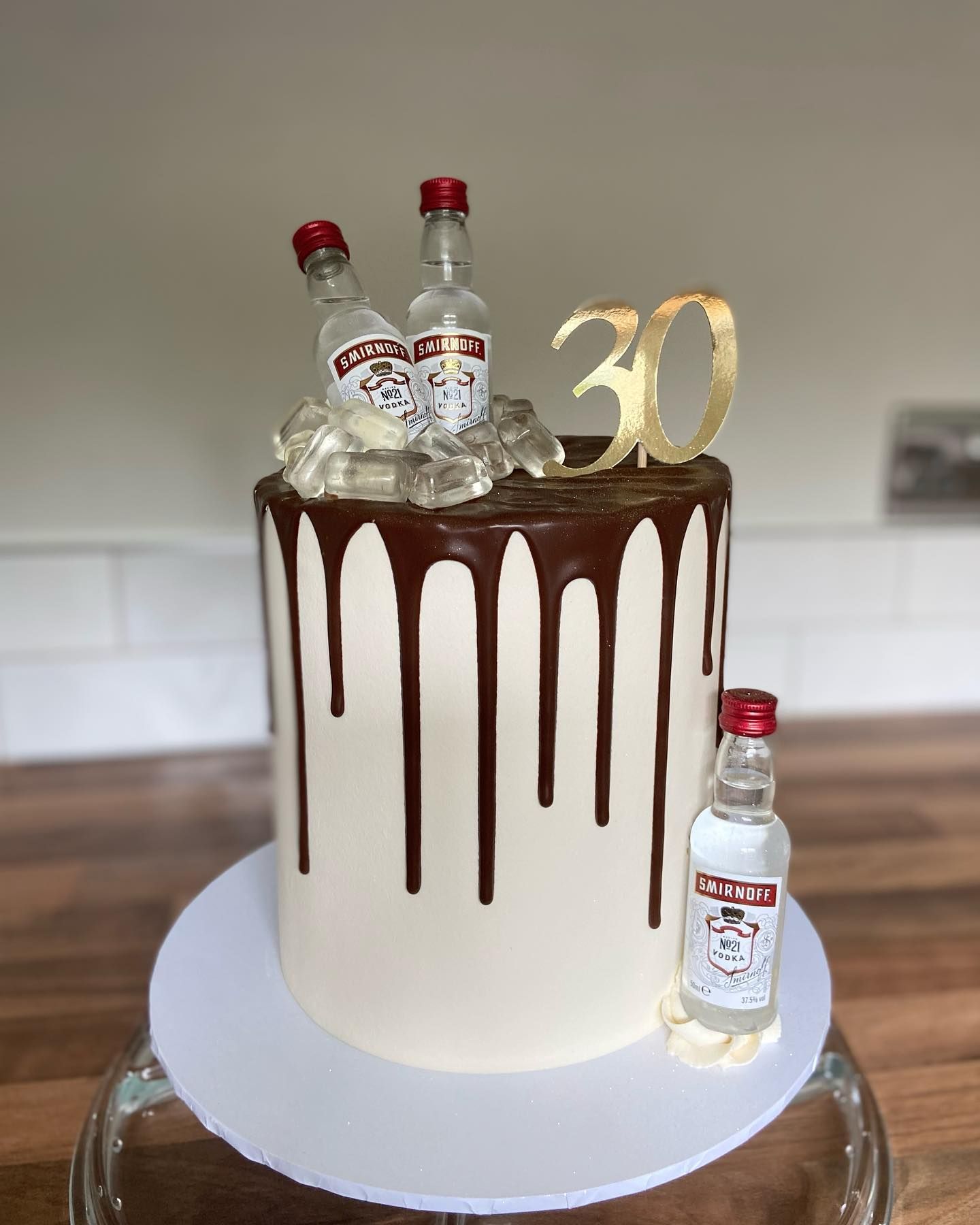 A cake with two bottles of smirnoff vodka on top of it.