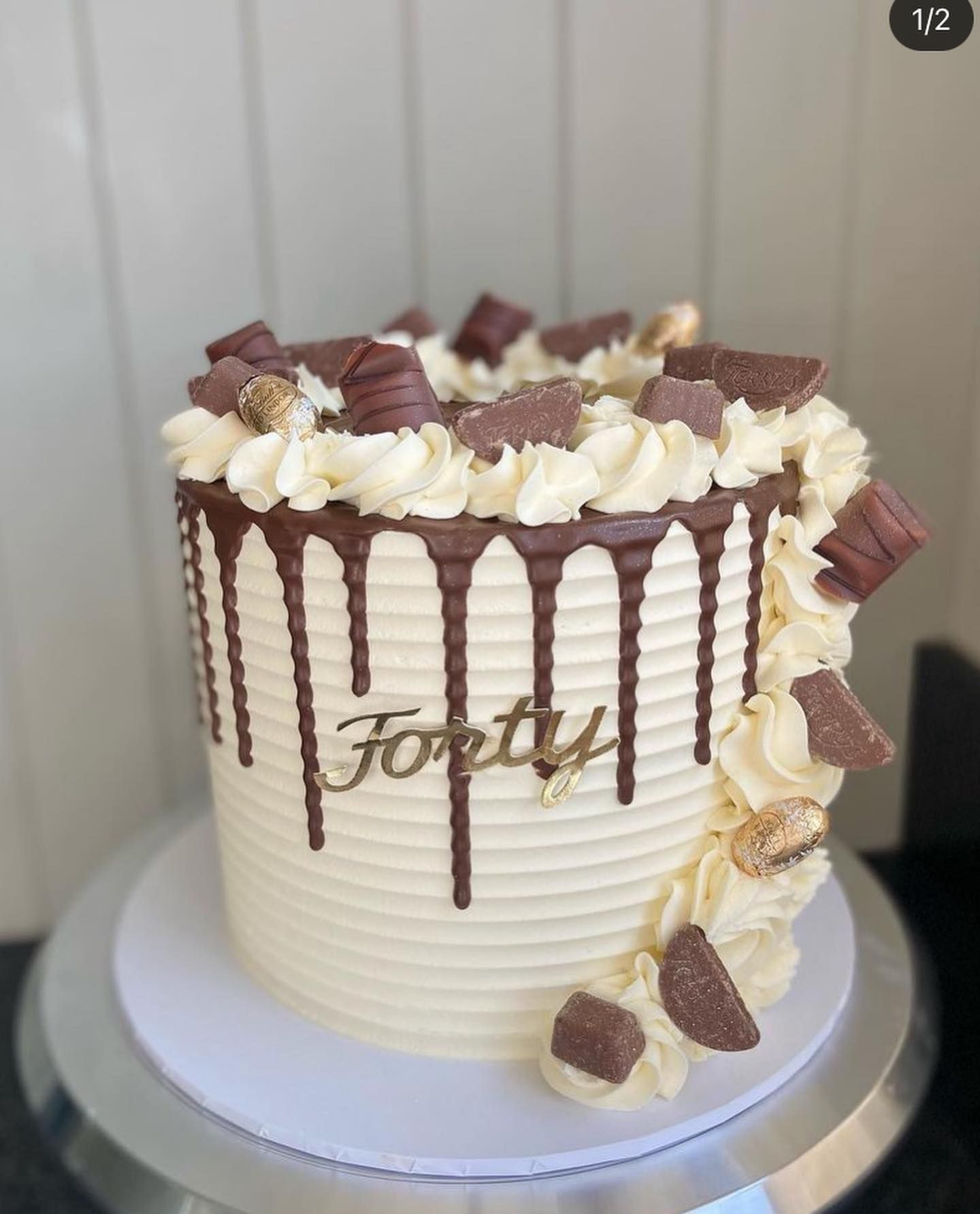 A white cake with chocolate drips and the word forty on it.