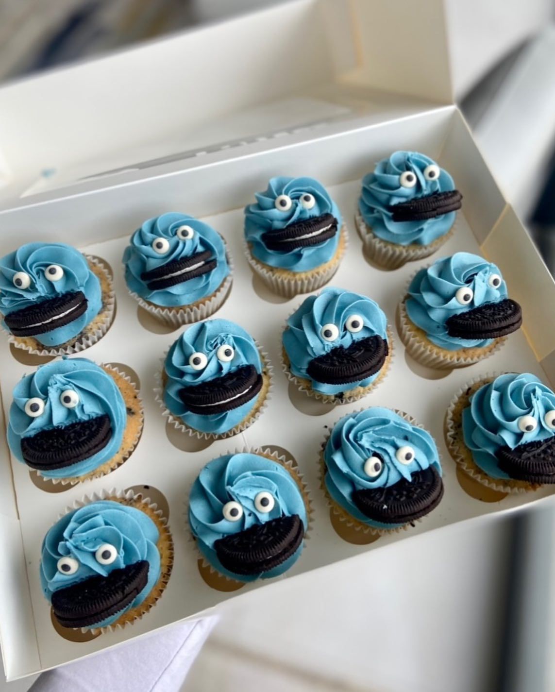 A box of cupcakes decorated to look like cookie monsters.