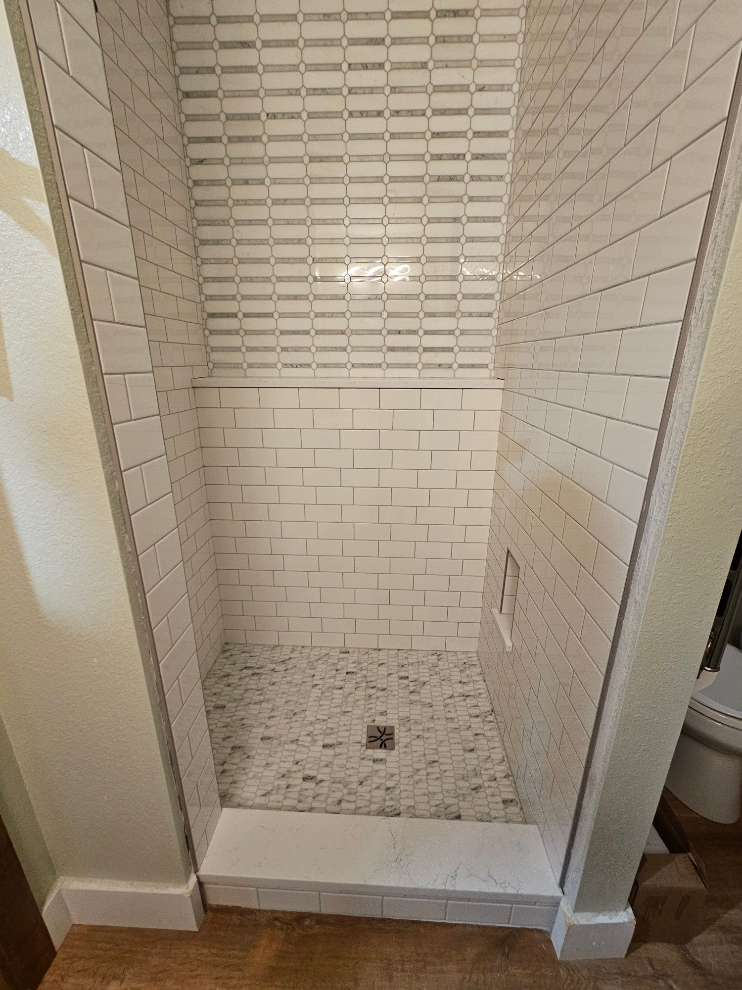 A shower stall with white tiles on the wall and floor.