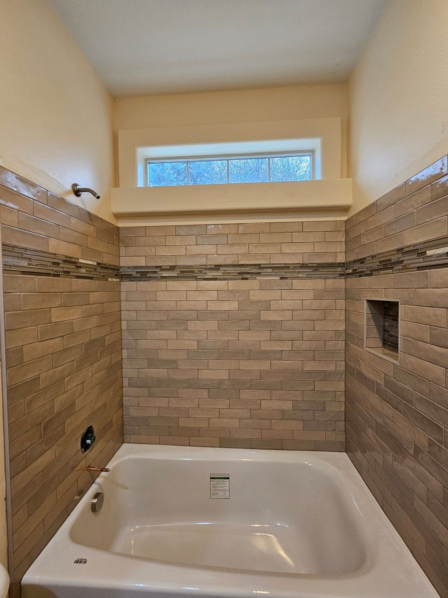 A bathtub in a bathroom with brick walls and a window.