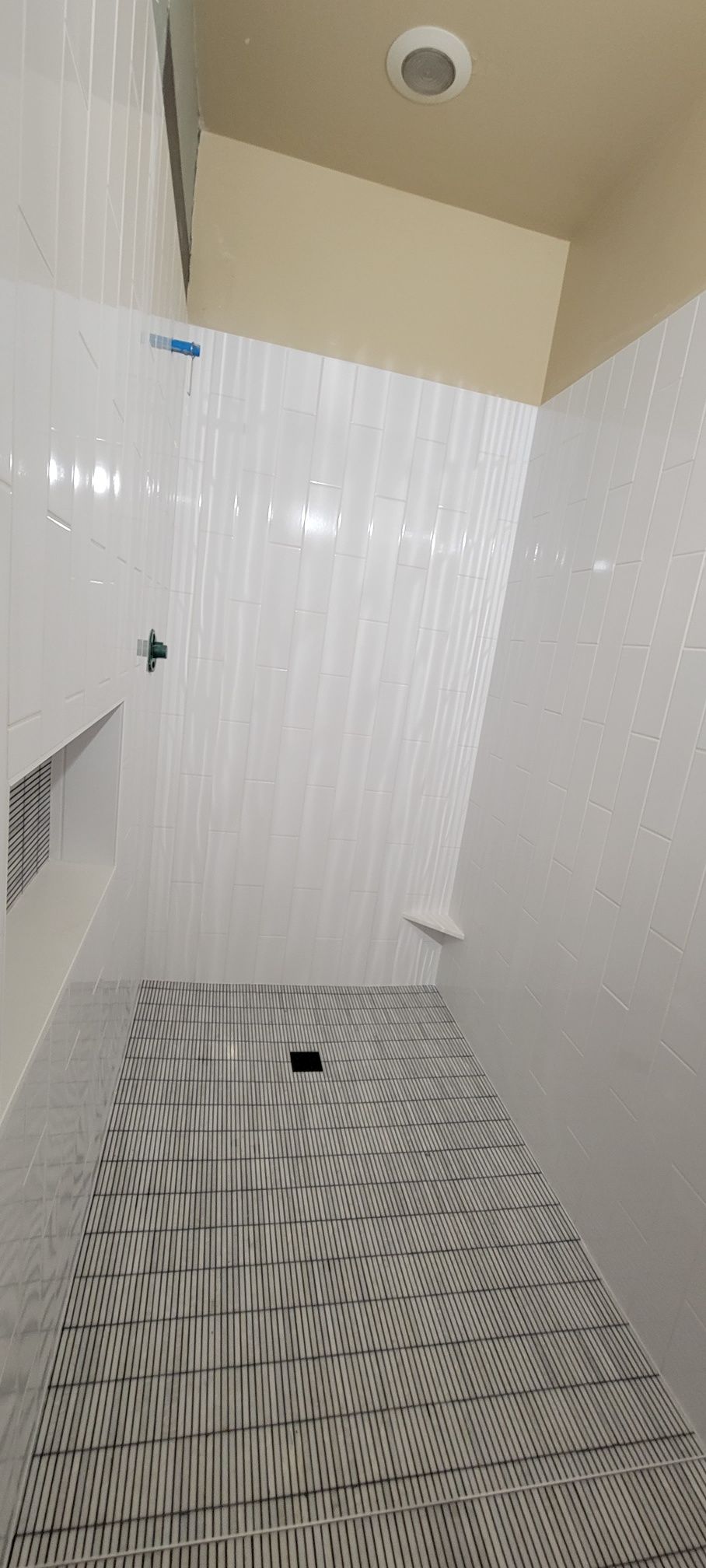 A bathroom with white tiles and a black and white tile floor.