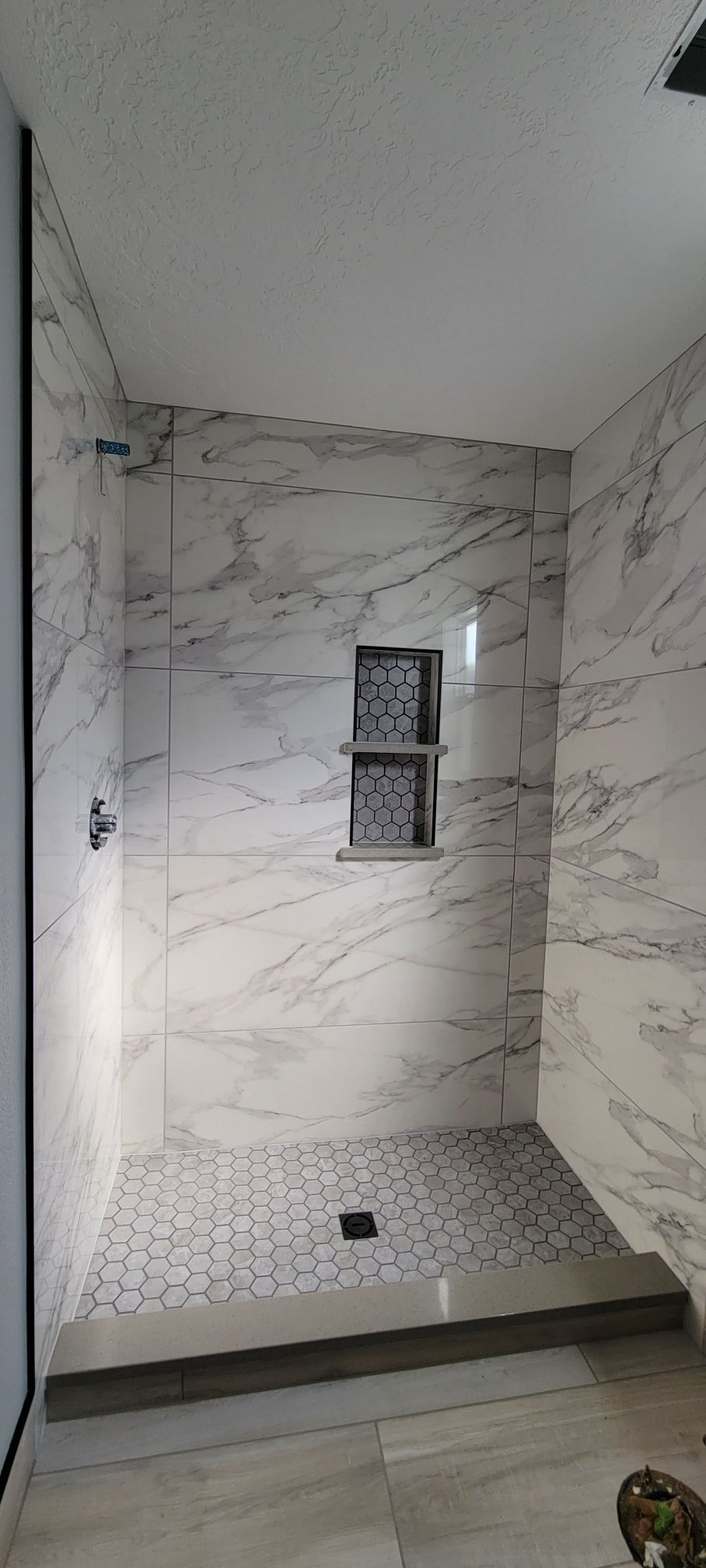 A bathroom with marble tiles and a walk in shower.