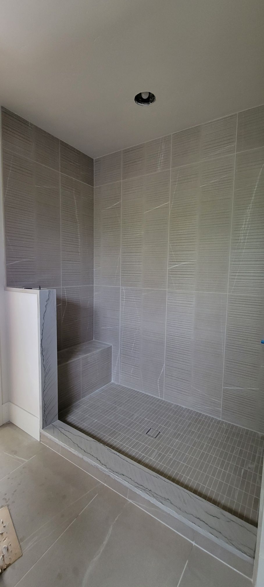 A bathroom with a walk in shower and tiled walls.