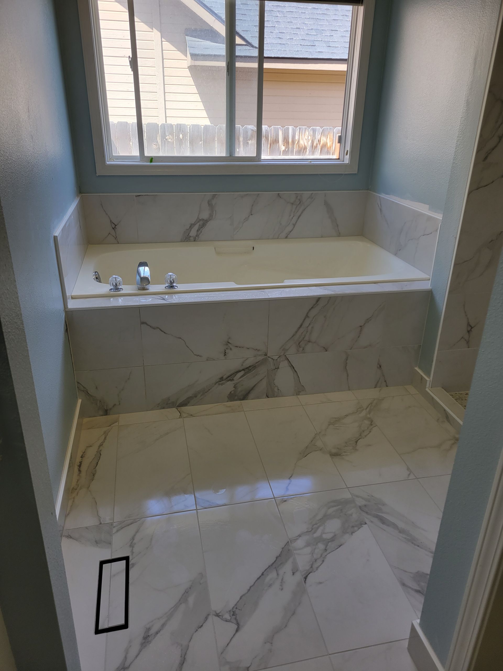 A bathroom with a marble bathtub and a window