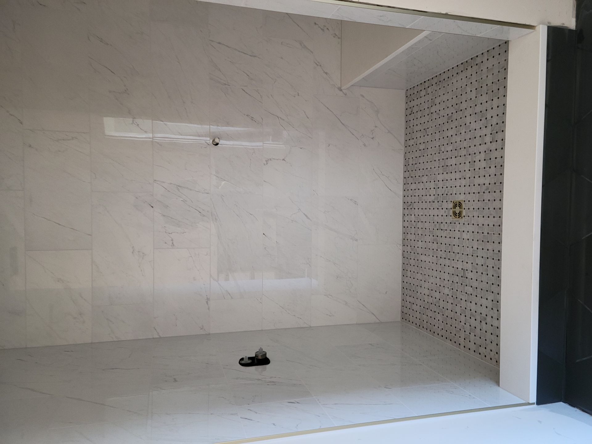 An empty room with white tiles and a black wall