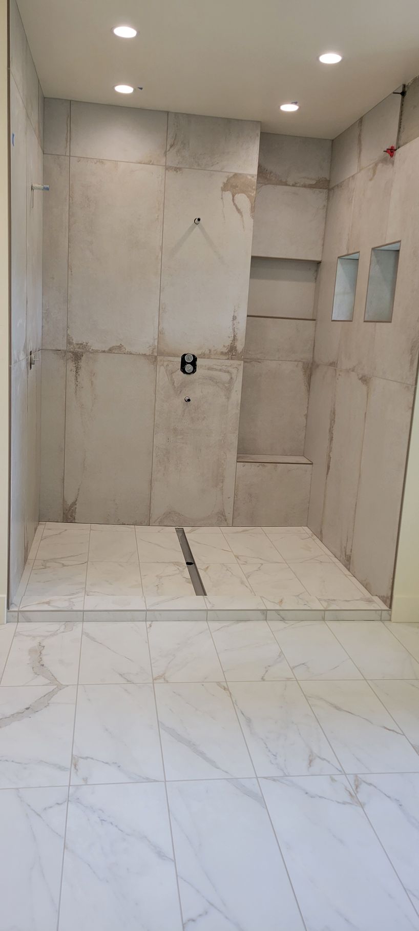 A bathroom with a walk in shower and a marble floor.