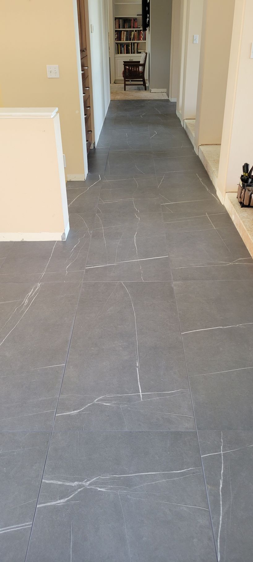 A long hallway with a gray tile floor in a house.