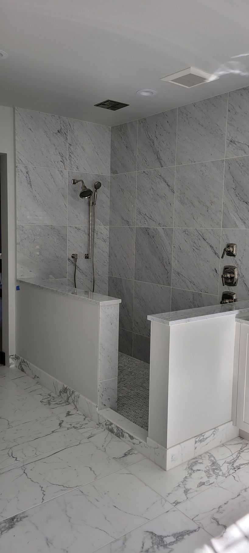 A bathroom with marble tiles and a walk in shower.