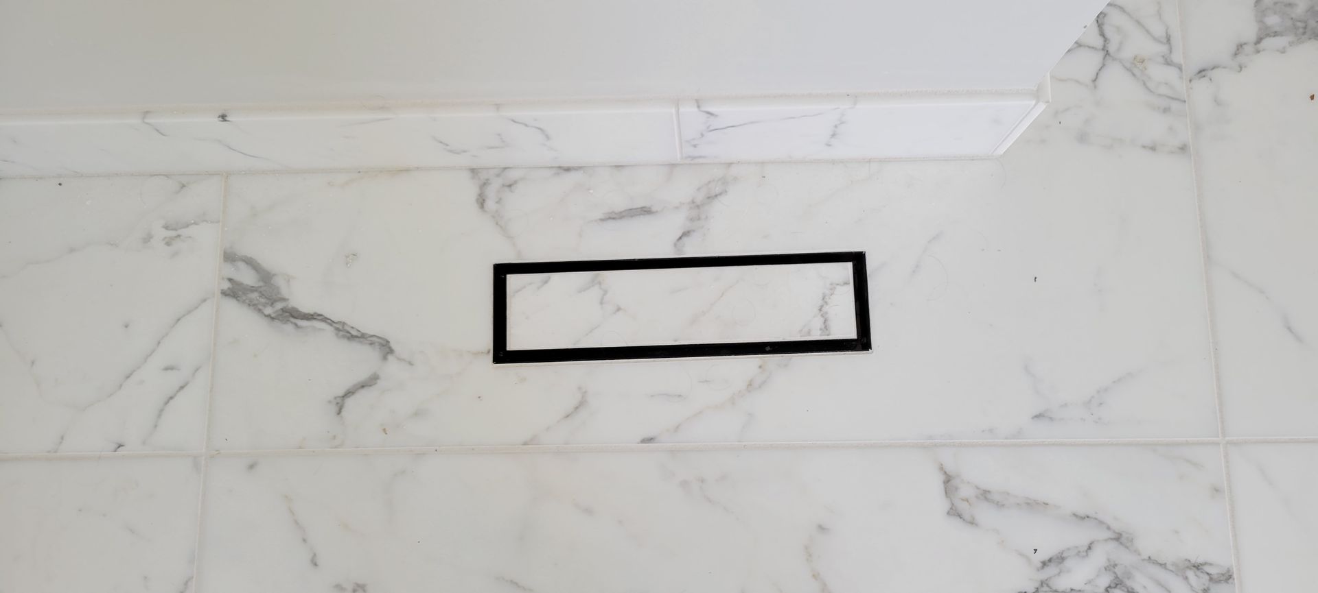 A black square is sitting on top of a white marble tile floor.