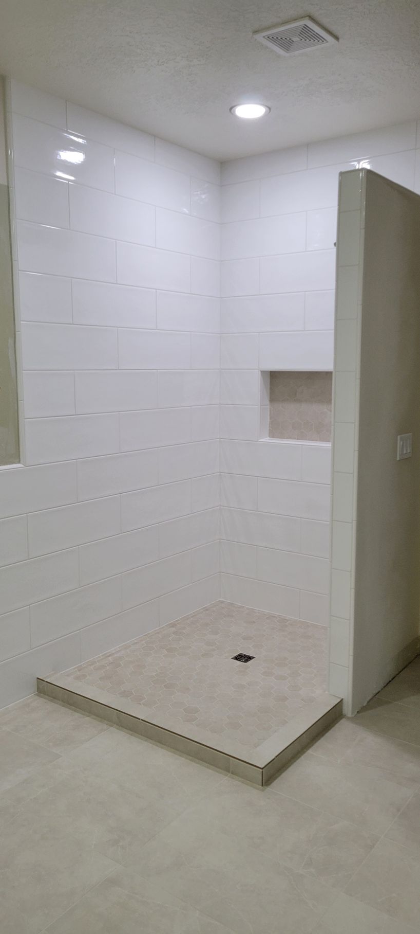 A bathroom with white tiles and a walk in shower.