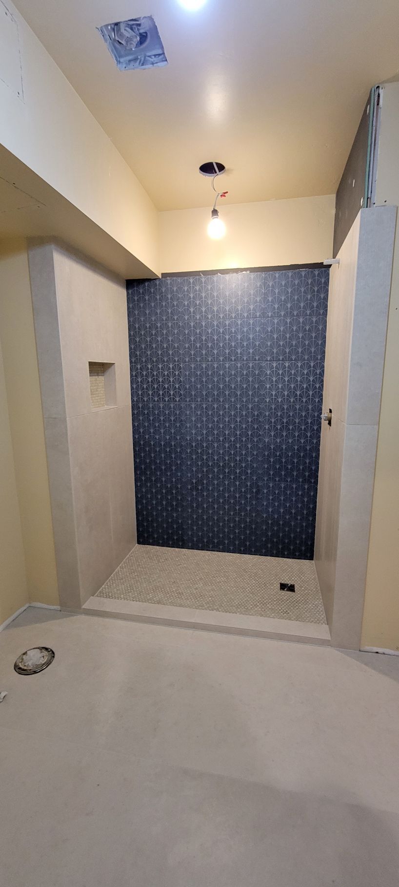 A bathroom with a walk in shower and a blue tiled wall.