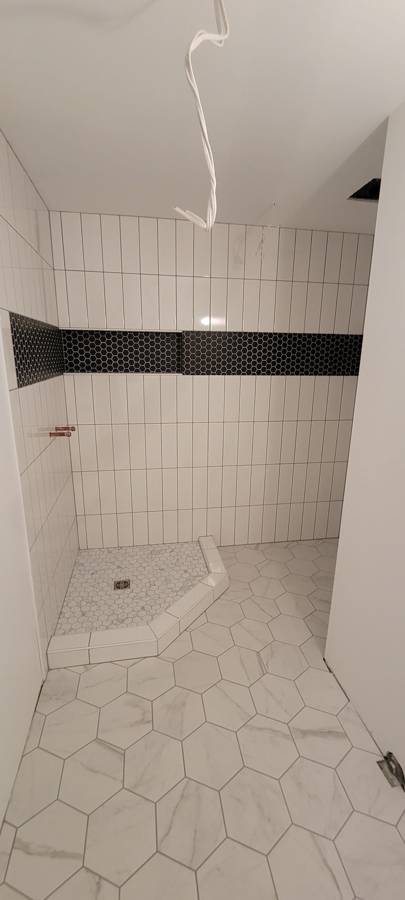 A bathroom with white tiles and a black stripe on the wall.