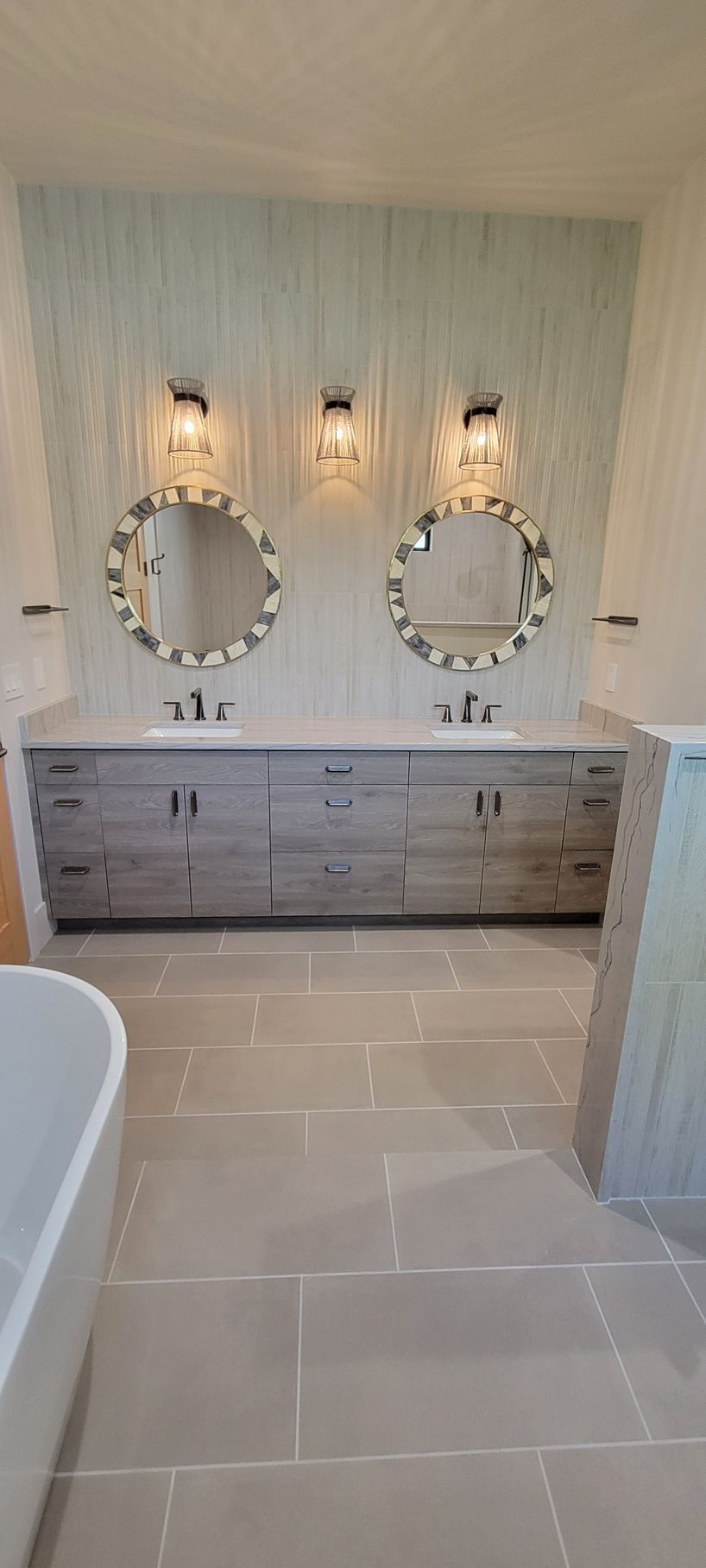 A bathroom with two sinks , two mirrors and a bathtub.