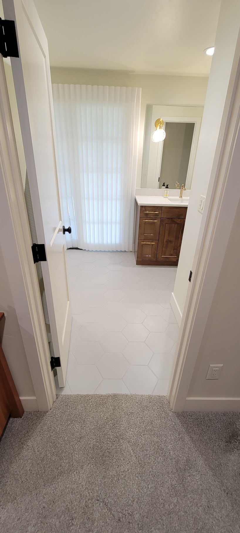 A hallway leading to a bathroom with a sink and mirror.