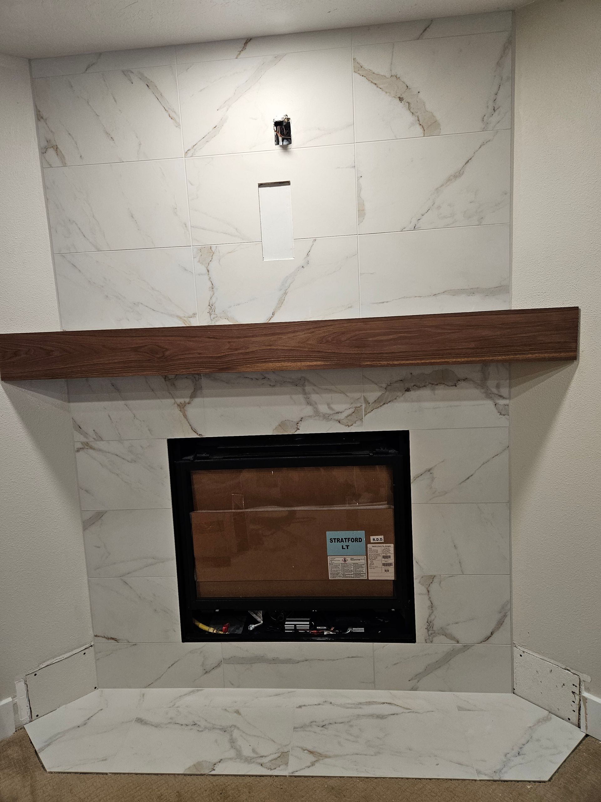 A fireplace with a wooden mantle in a living room.