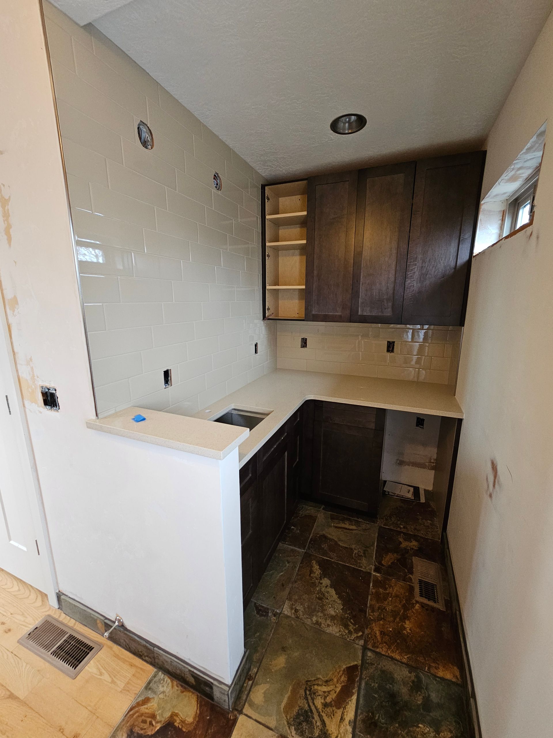 A kitchen with a sink , cabinets , and tile floor.