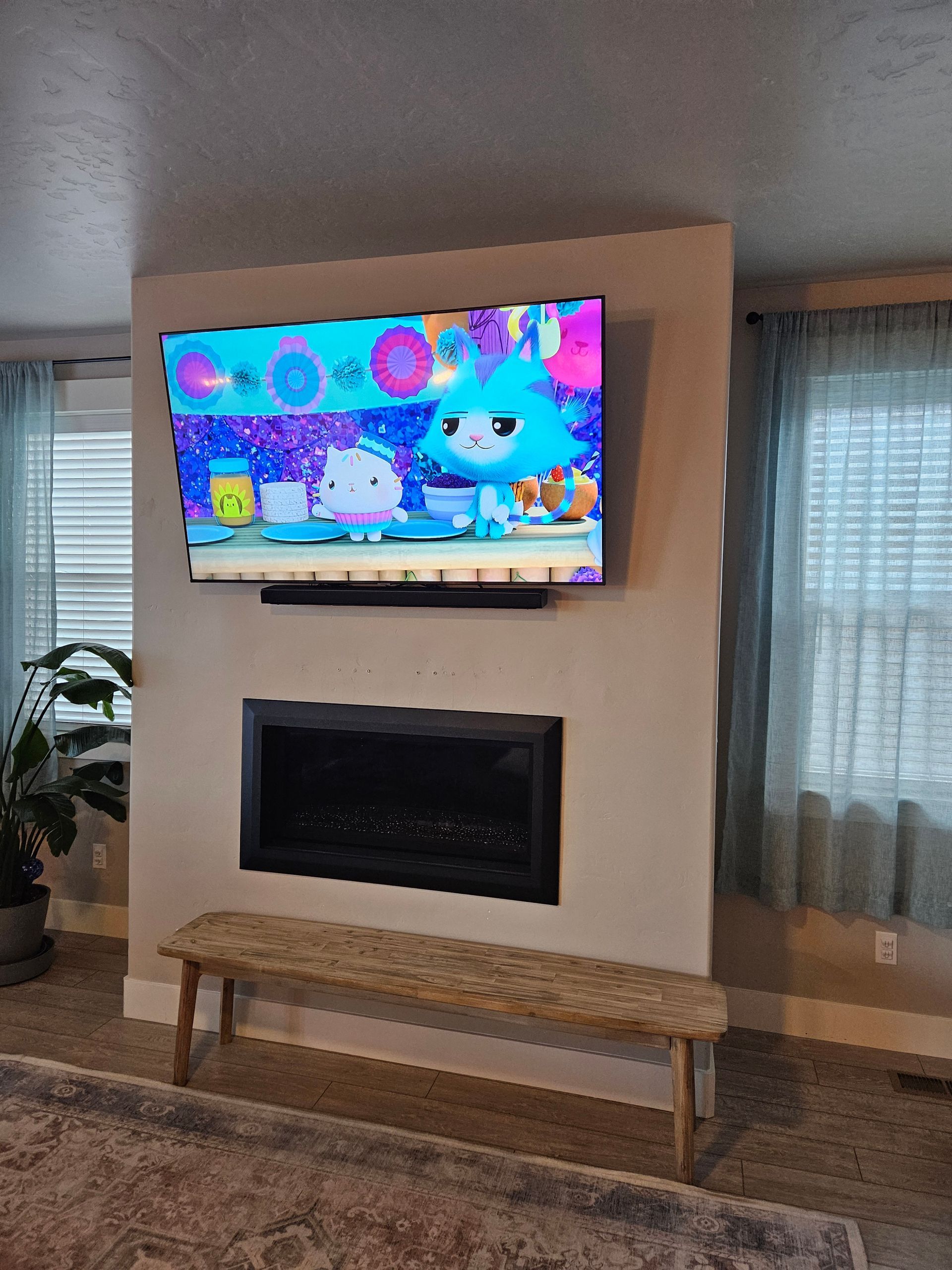 A living room with a fireplace and a flat screen tv on the wall.