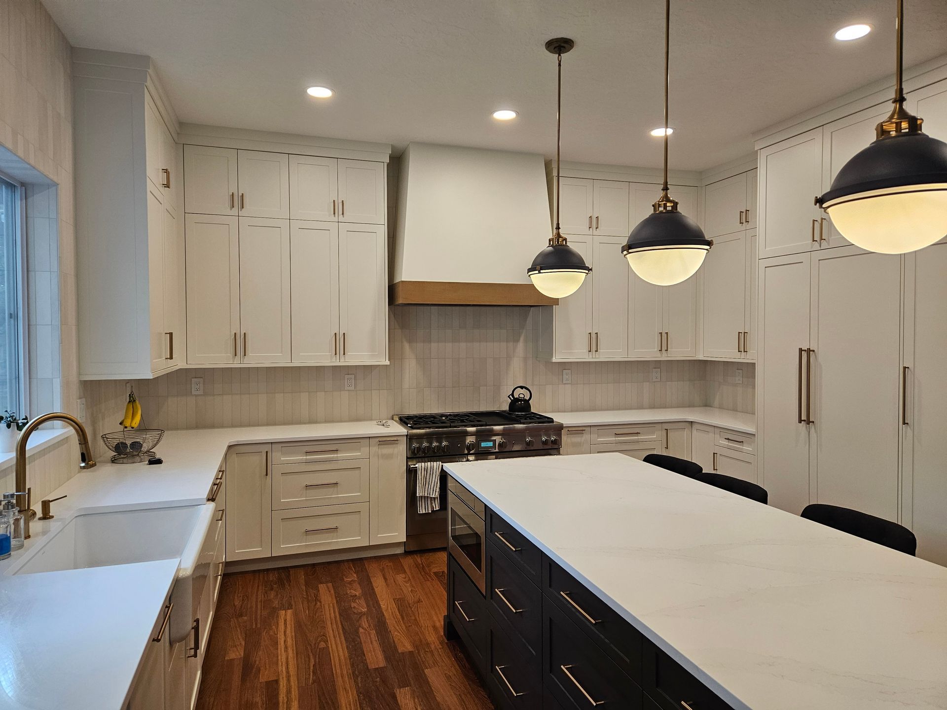 A kitchen with white cabinets , black cabinets , and a large island.