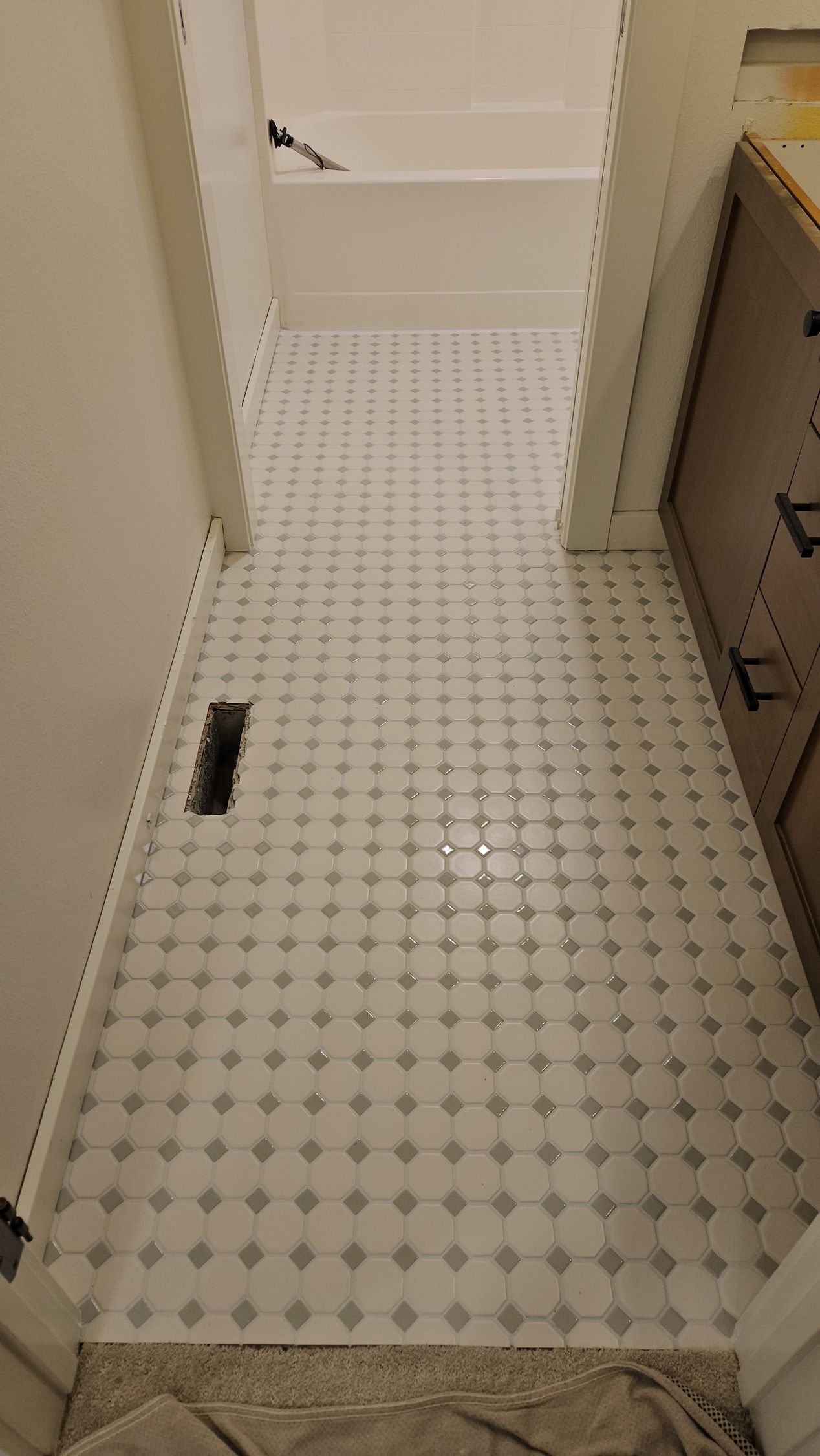 A bathroom with a white tile floor and a bathtub.