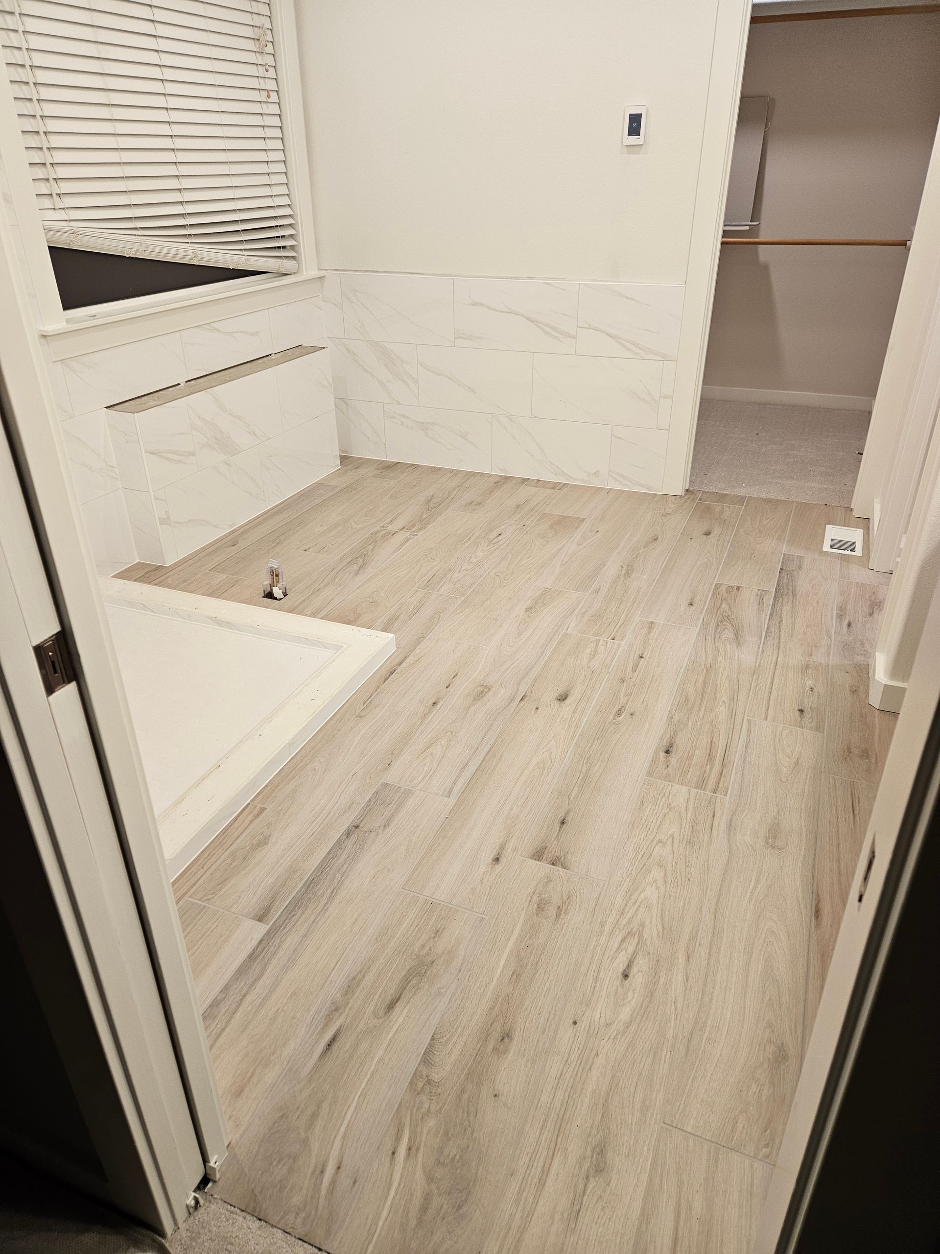 A bathroom with a wooden floor and a tub.