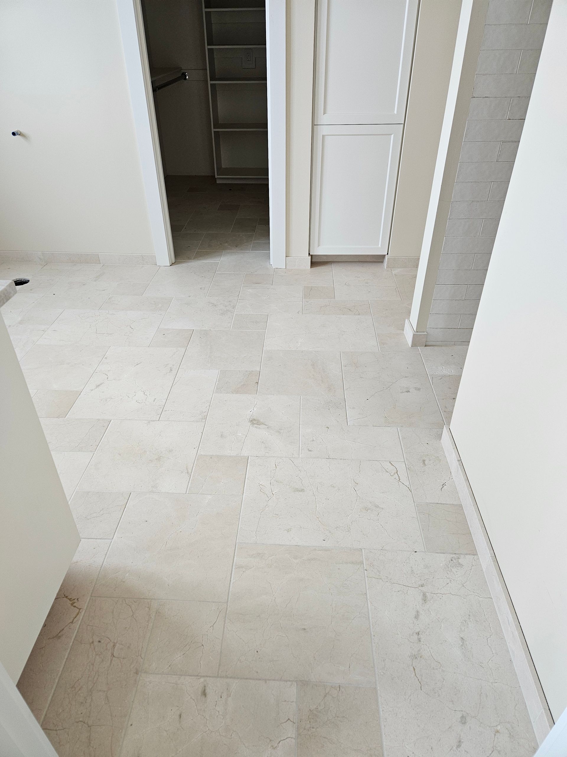 A white tiled floor in a room with a refrigerator