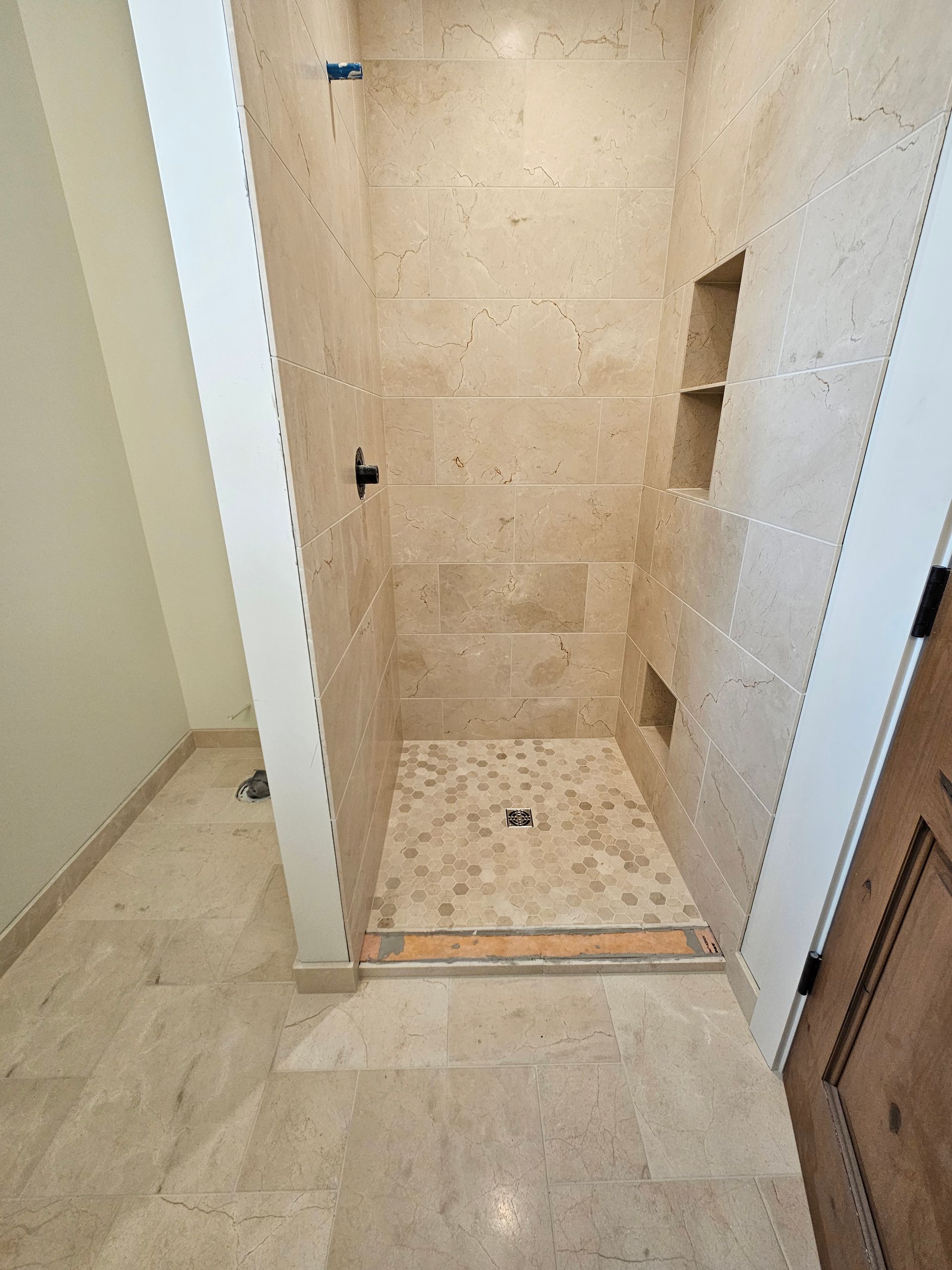 A bathroom with a walk in shower and a wooden door.
