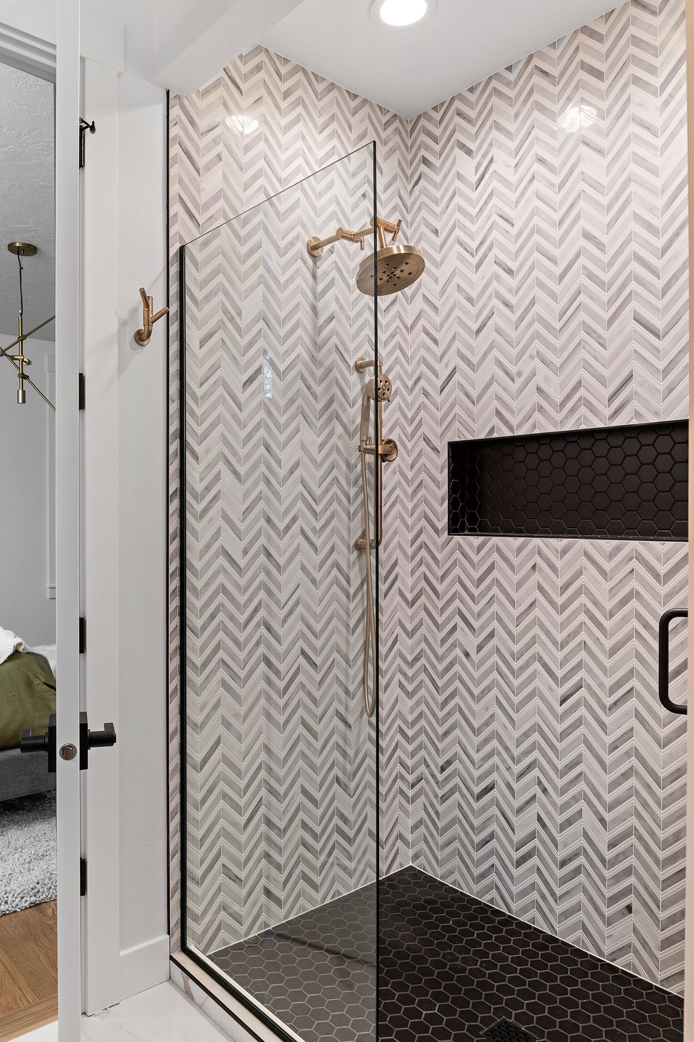 A bathroom with a walk in shower with a glass door and a shower head.
