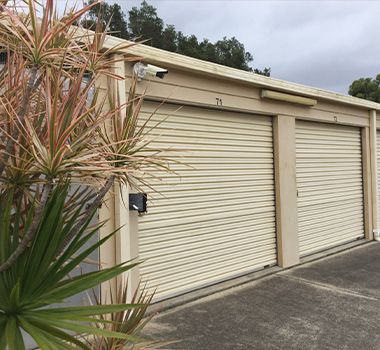 A row of garage doors with a plant in front of them.