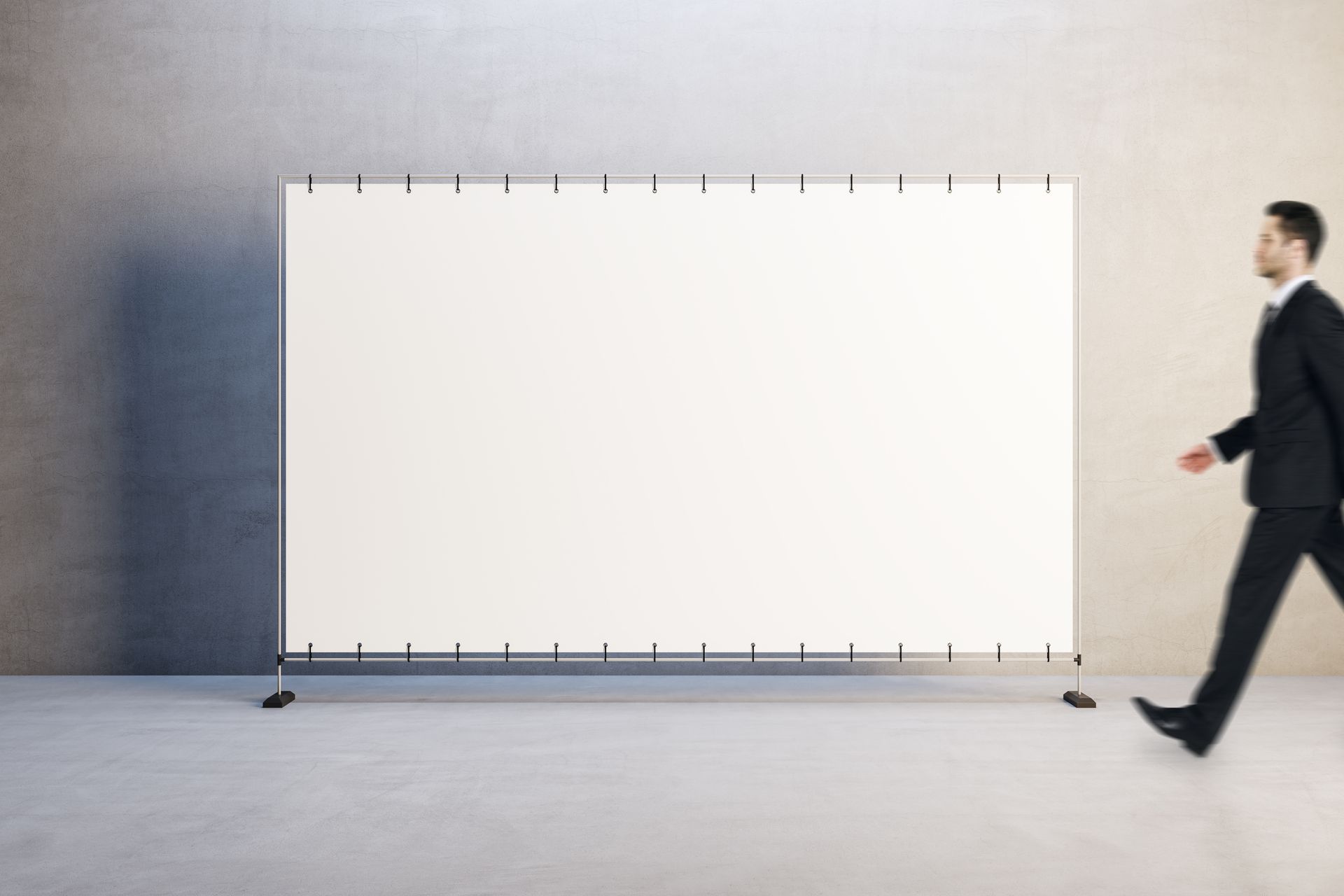 A man in a suit is walking past a large white board.