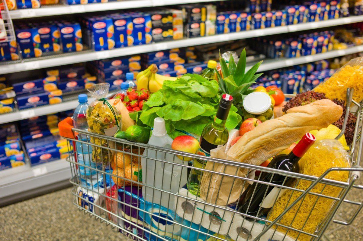 In il carrello della spesa va pasta,la verdura, la frutta,pane,vino,acqua e prodotti per la pulizia