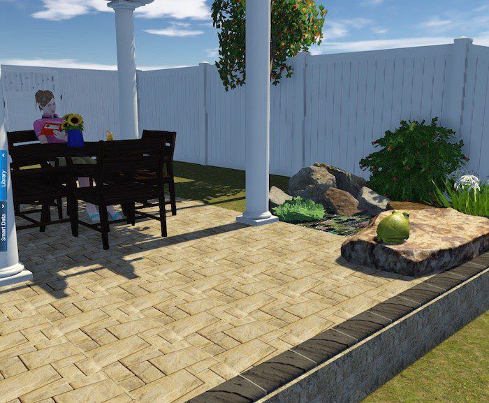 Patio with a table and chairs, stone walkway, pillars, fence, rocks, and a green bush.